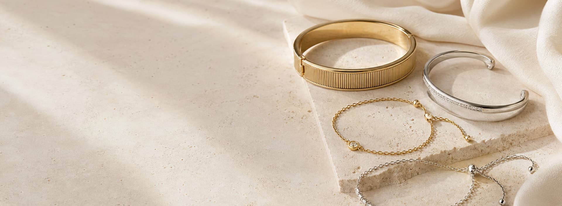 Bracelets et joncs dorés et argentés sur textile ivoire