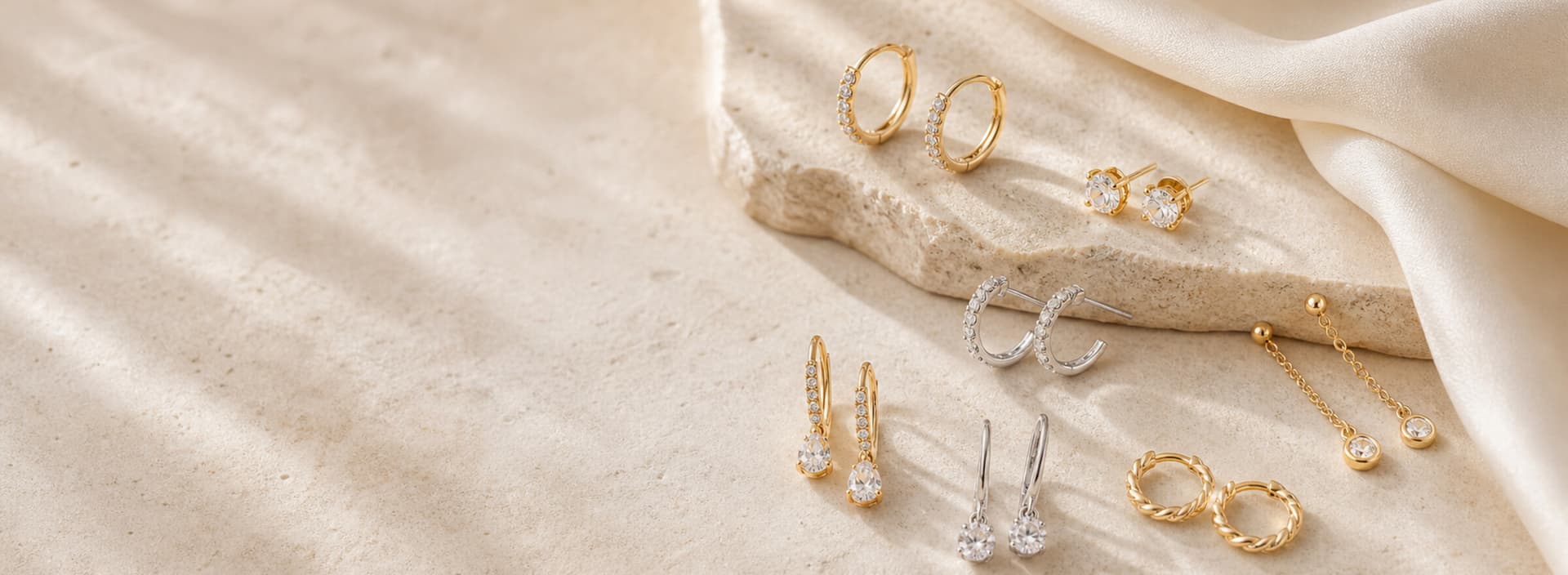 Boucles d'oreilles dorées et argentées sur tissu ivoire
